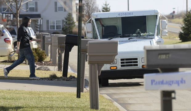 A U.S. Postal Service letter carrier walks back to his van after delivering a package along Shepard Road, east of Blackstone Boulevard in Normal in December. Some subdivisions won't have the convenience of curbside mailboxes under a change by the Postal Service.